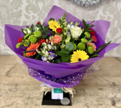 Vibrant Celebration Bouquet - A bold and lively bouquet with a mix of bright oranges, blues, and yellows, elegantly wrapped in paper, perfect for any celebration.